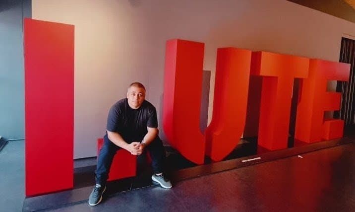 Paulo sentado em uma instalação de letras gigantes em um evento